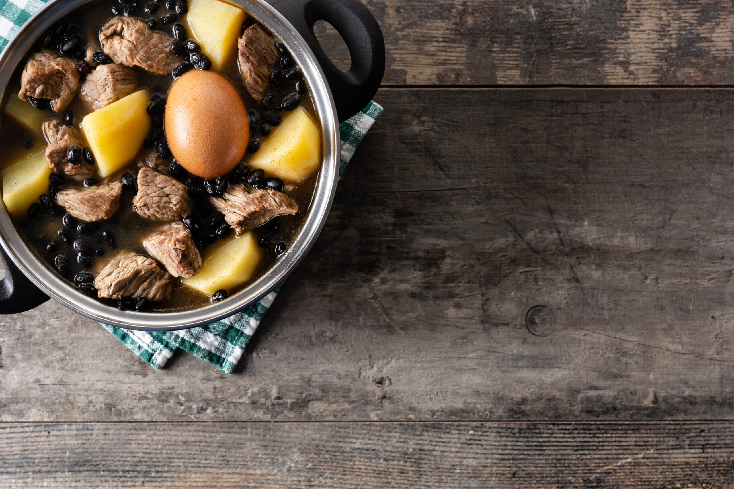 Traditional Jewish cholent in casserole on wooden table