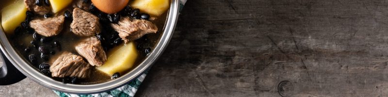 Traditional Jewish cholent in casserole on wooden table
